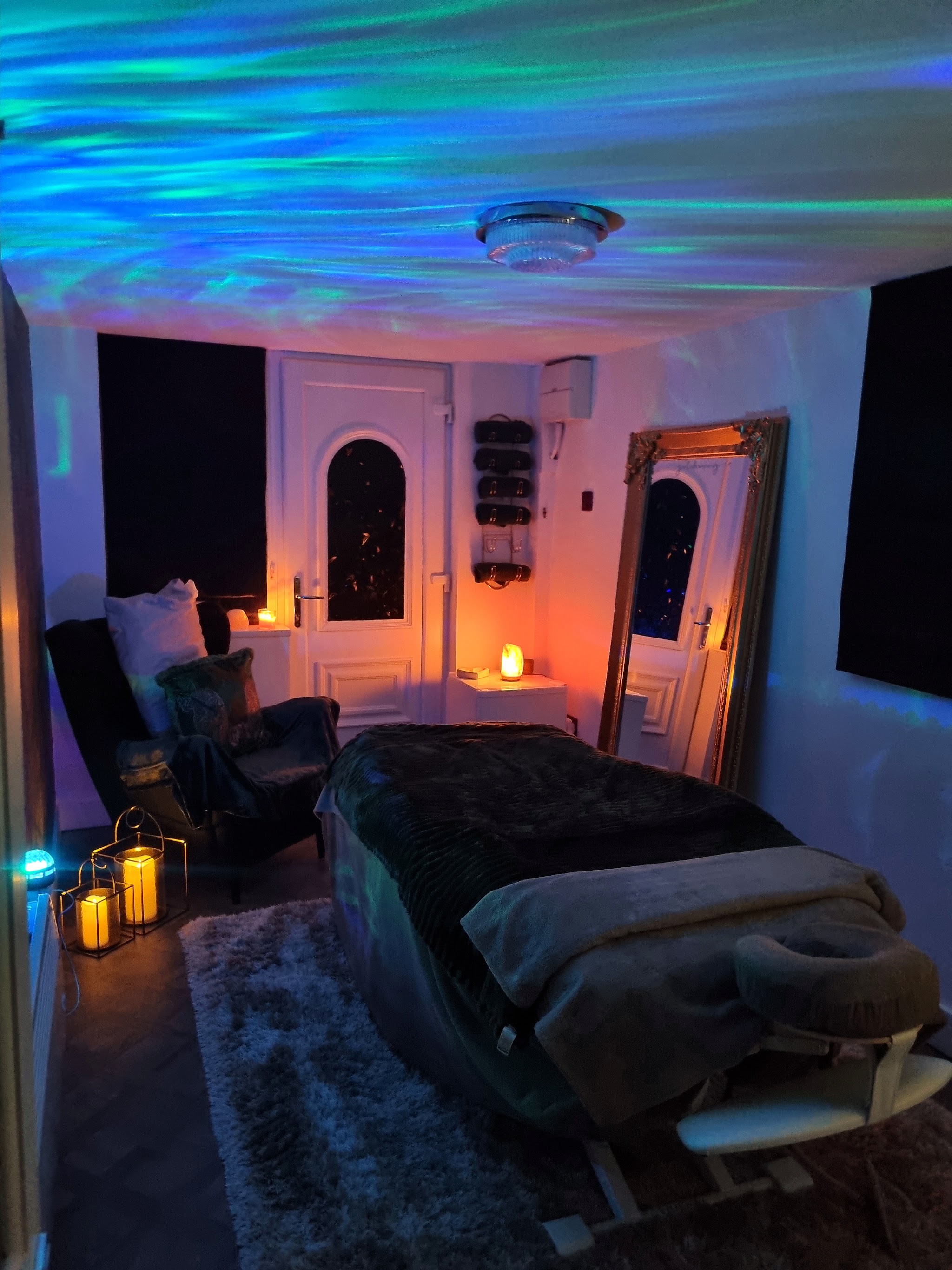 The candlelit massage room at R&R by Zoe, with a cosy treatment bed and calming coloured light