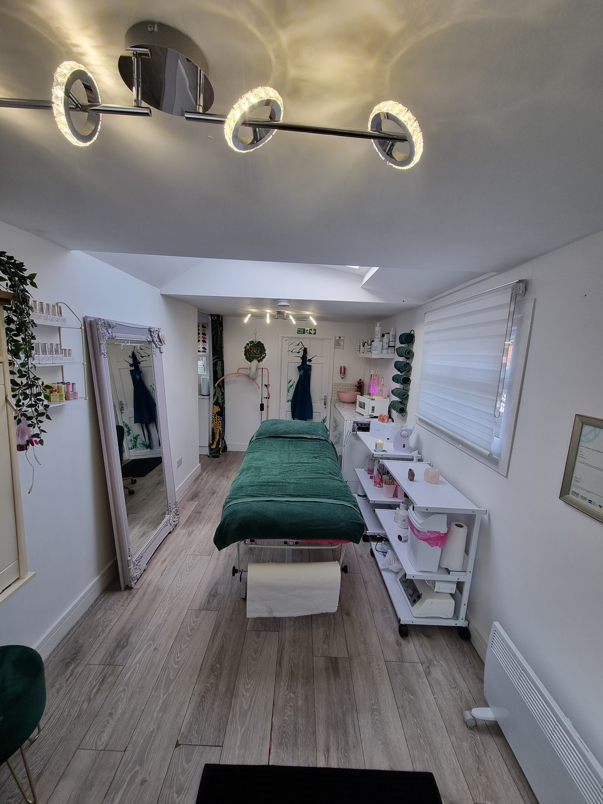 The bright treatment room at R&R by Zoe, with a green treatment bed, mirror and skincare products